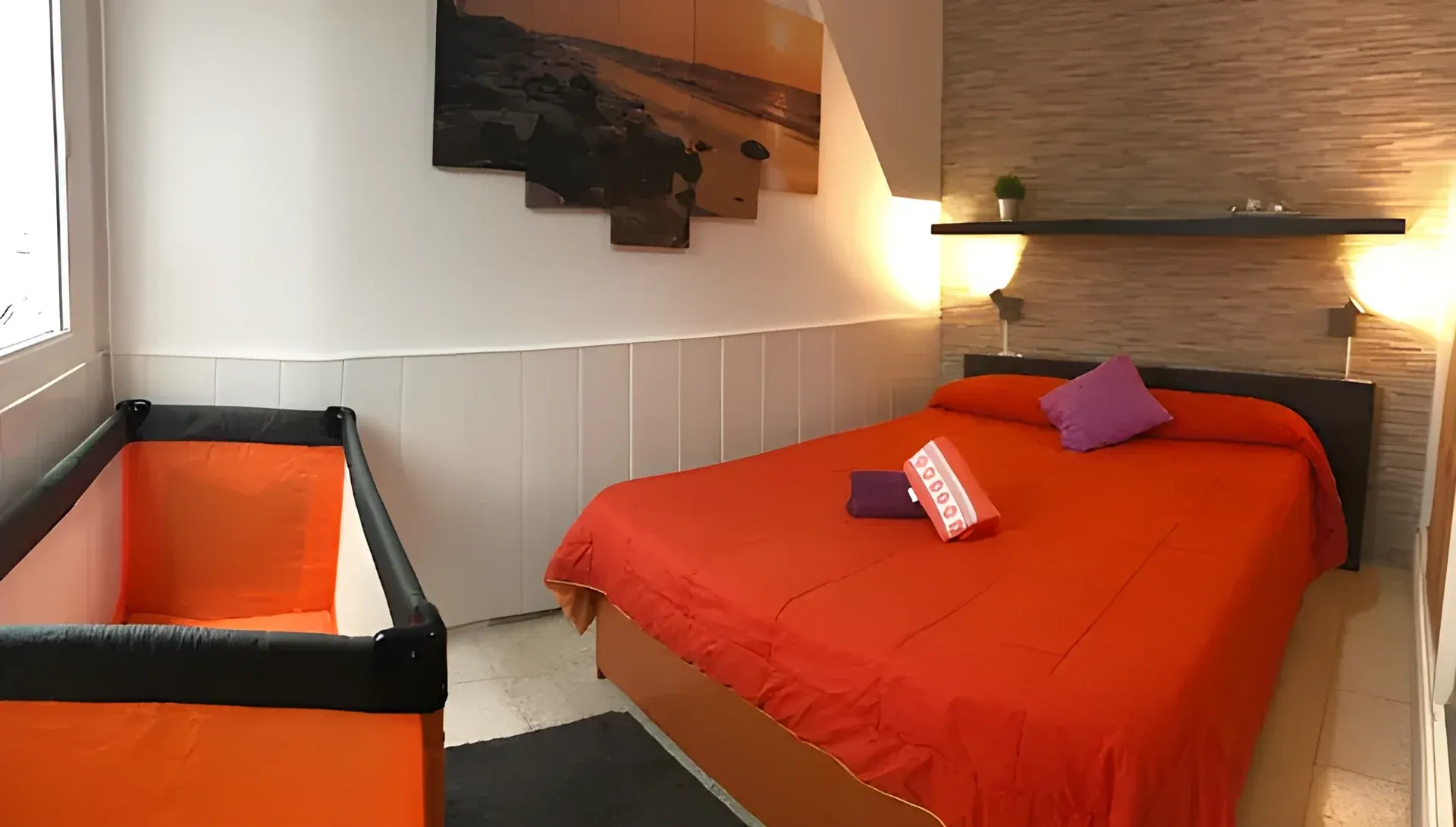 Dormitorio con cama de matrimonio y cuna de viaje