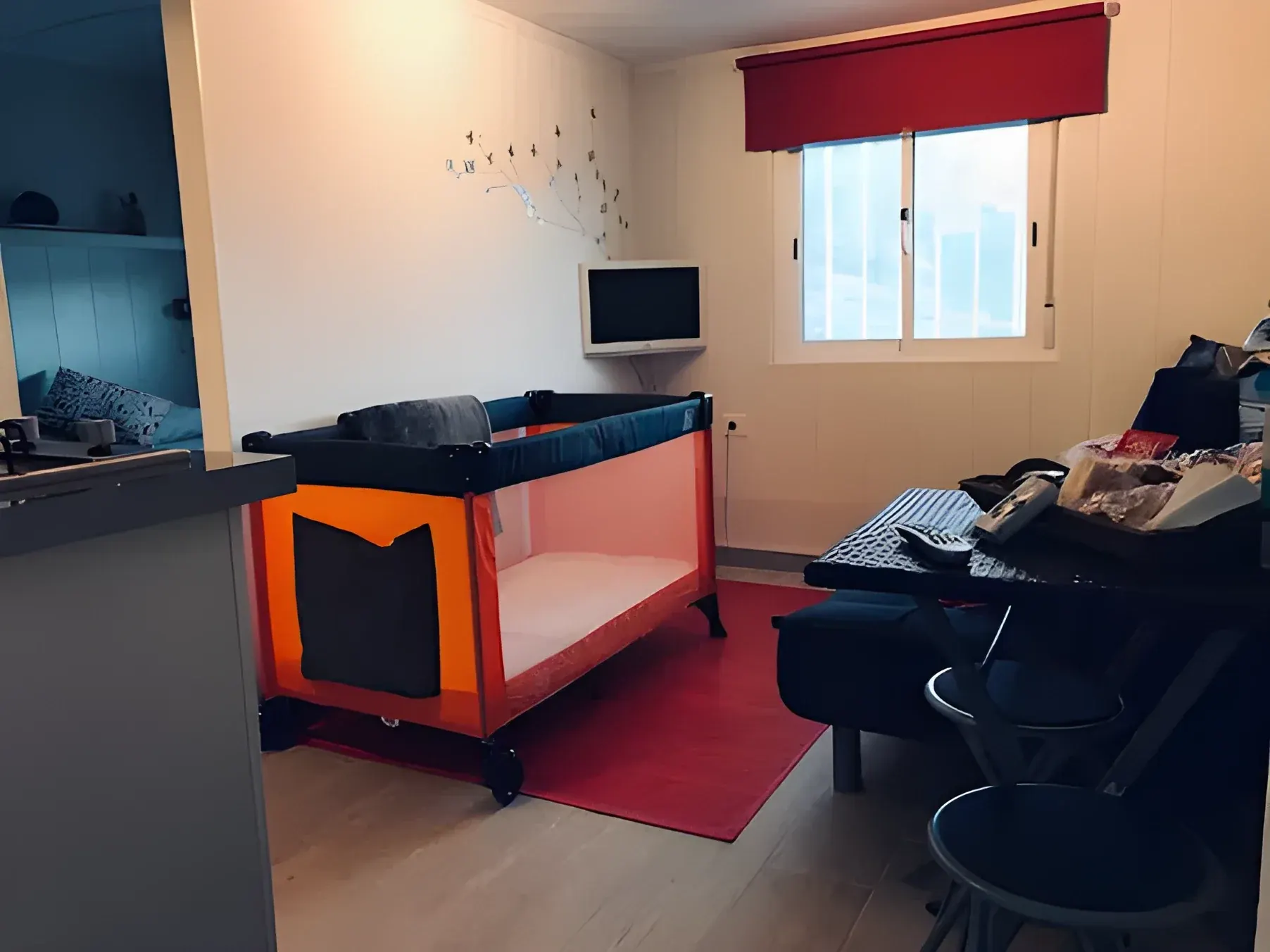 Salón con sofá, televisión y cuna de viaje