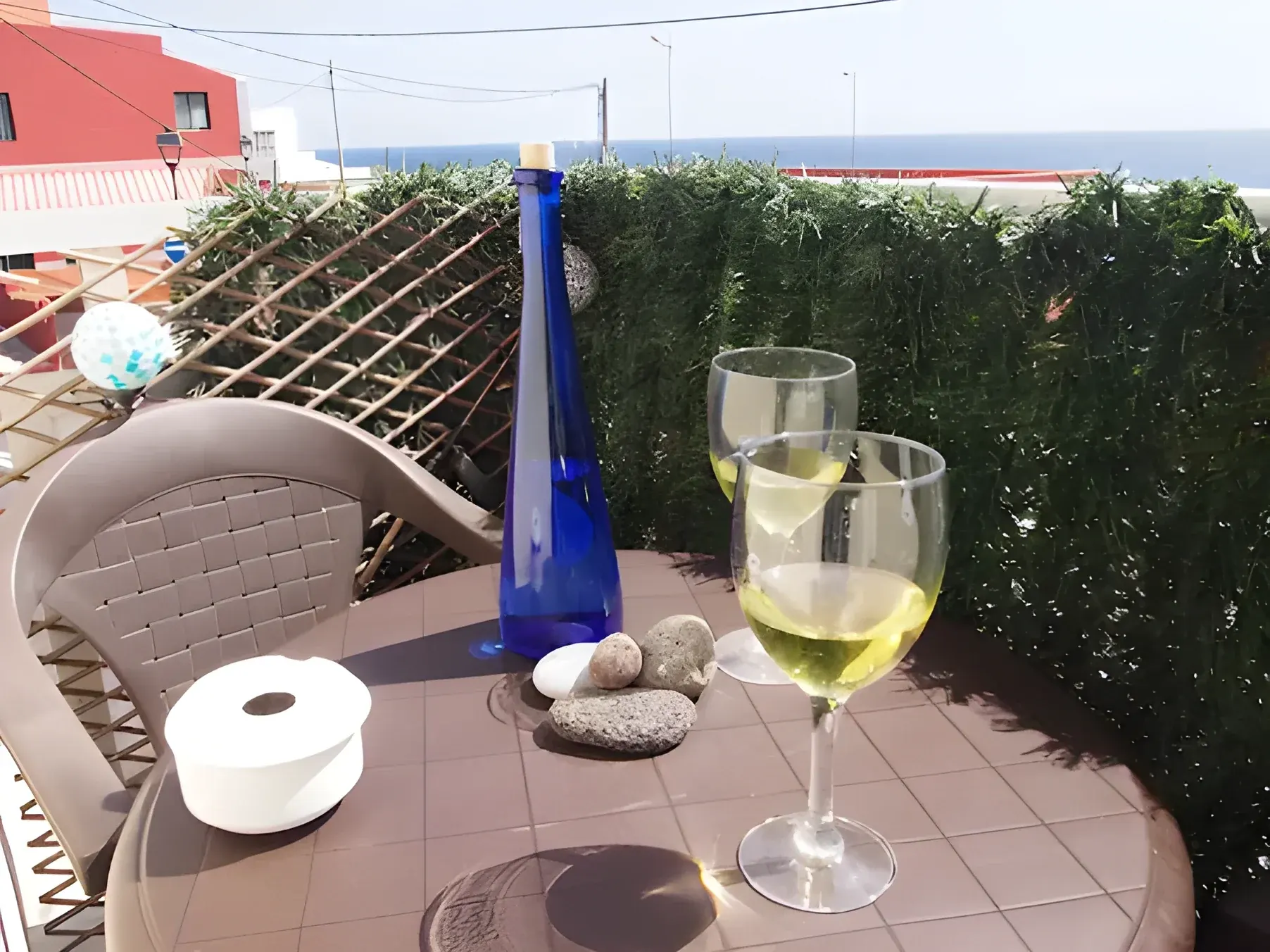 Mesa de la terraza preparada con dos copas de vino y vistas al mar