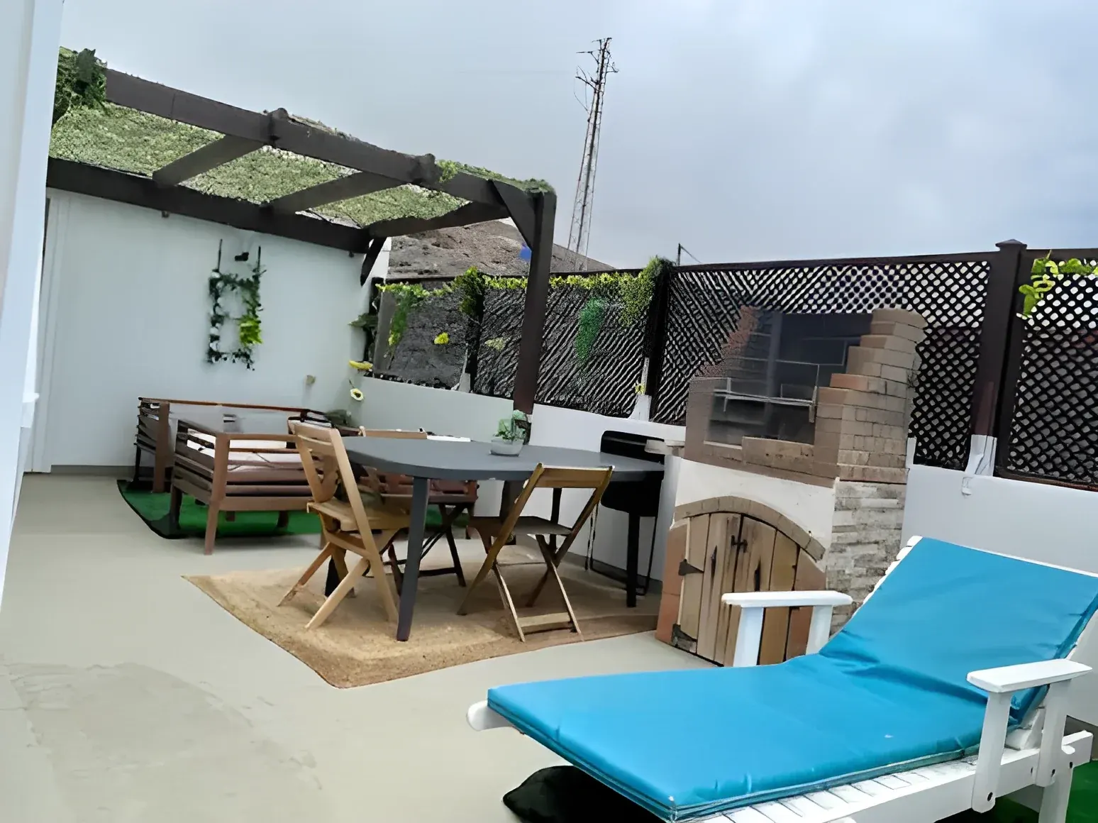 Terraza con pérgola, tumbona y zona de comedor exterior